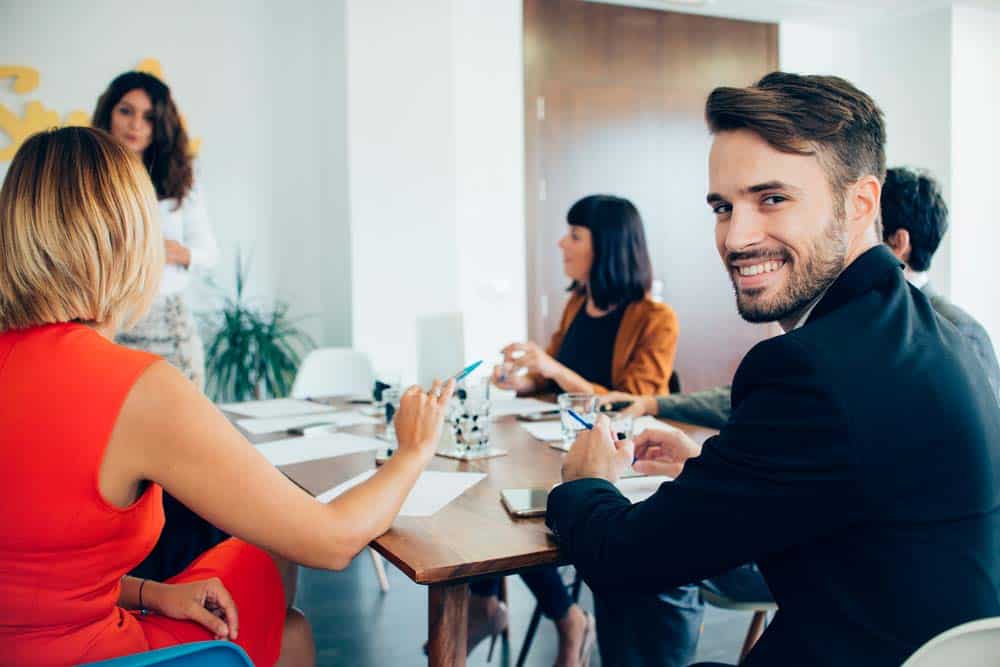 Smiling team member looking up from a planning meeting around a boardroom table