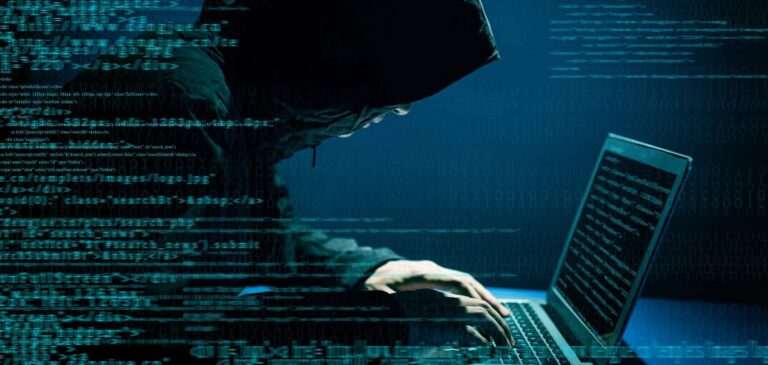 Hooded figure typing on a laptop surrounded by lines of code
