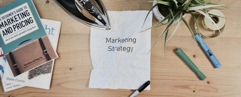 Crumpled paper reading Marketing Strategy on a desk with books and pens