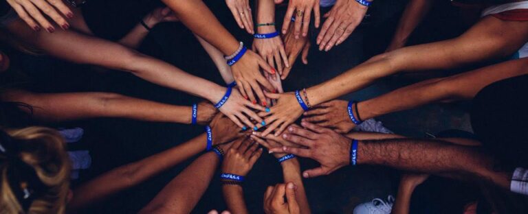 Group of hands joined in the centre, wearing matching wristbands