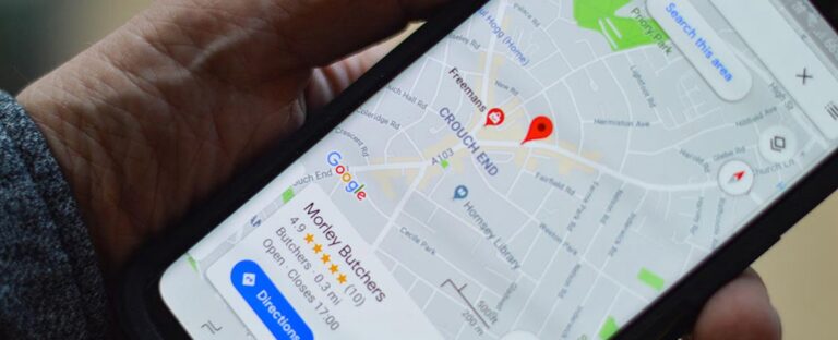 Hand holding a phone showing Google Maps business listings nearby