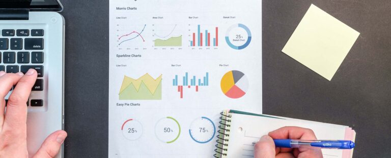 Laptop and printed charts on a desk during a reporting review