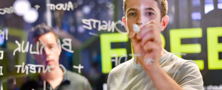 Man writing on a glass board, with the word FREE in the background