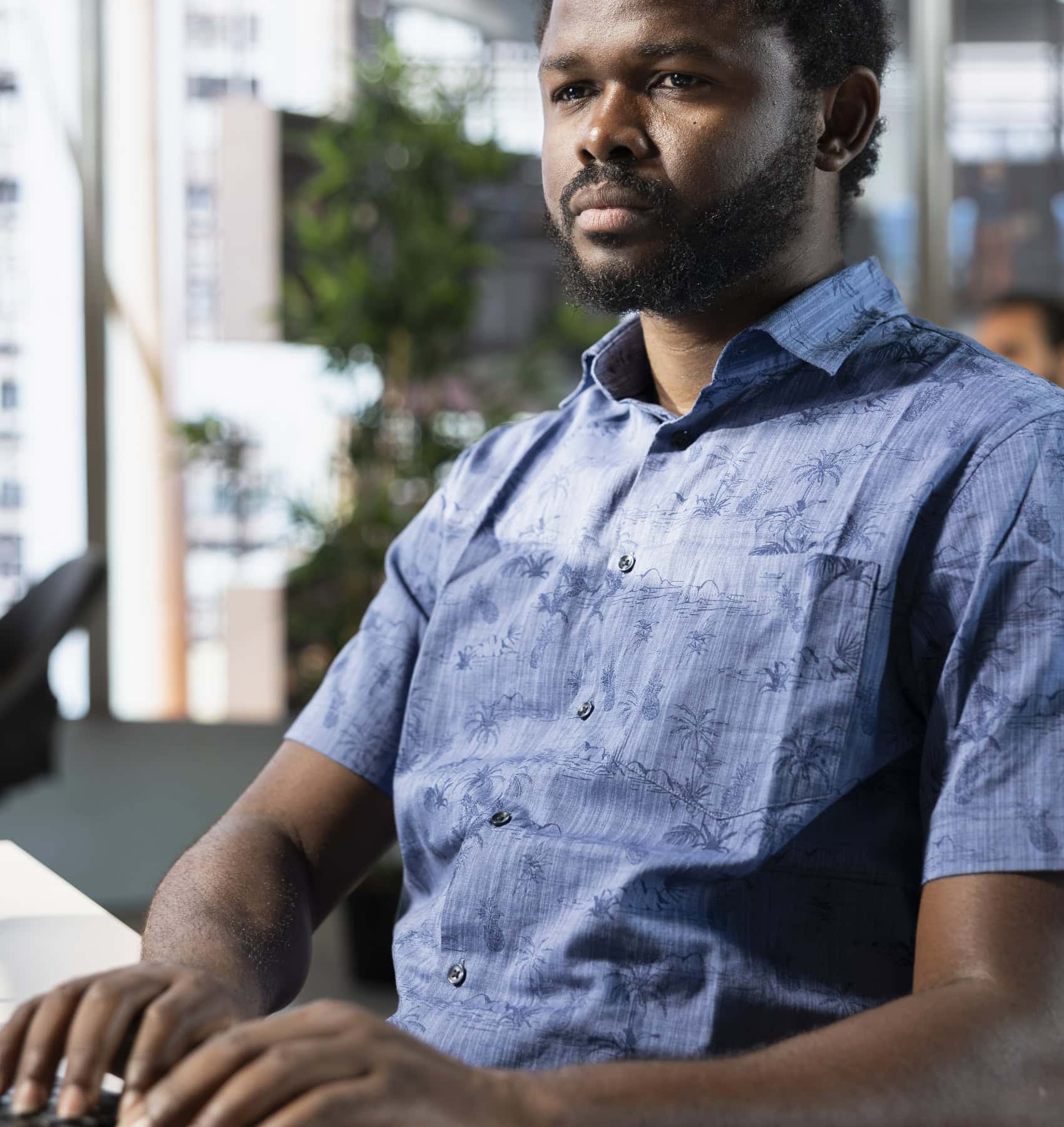 Man typing at a laptop in a bright office
