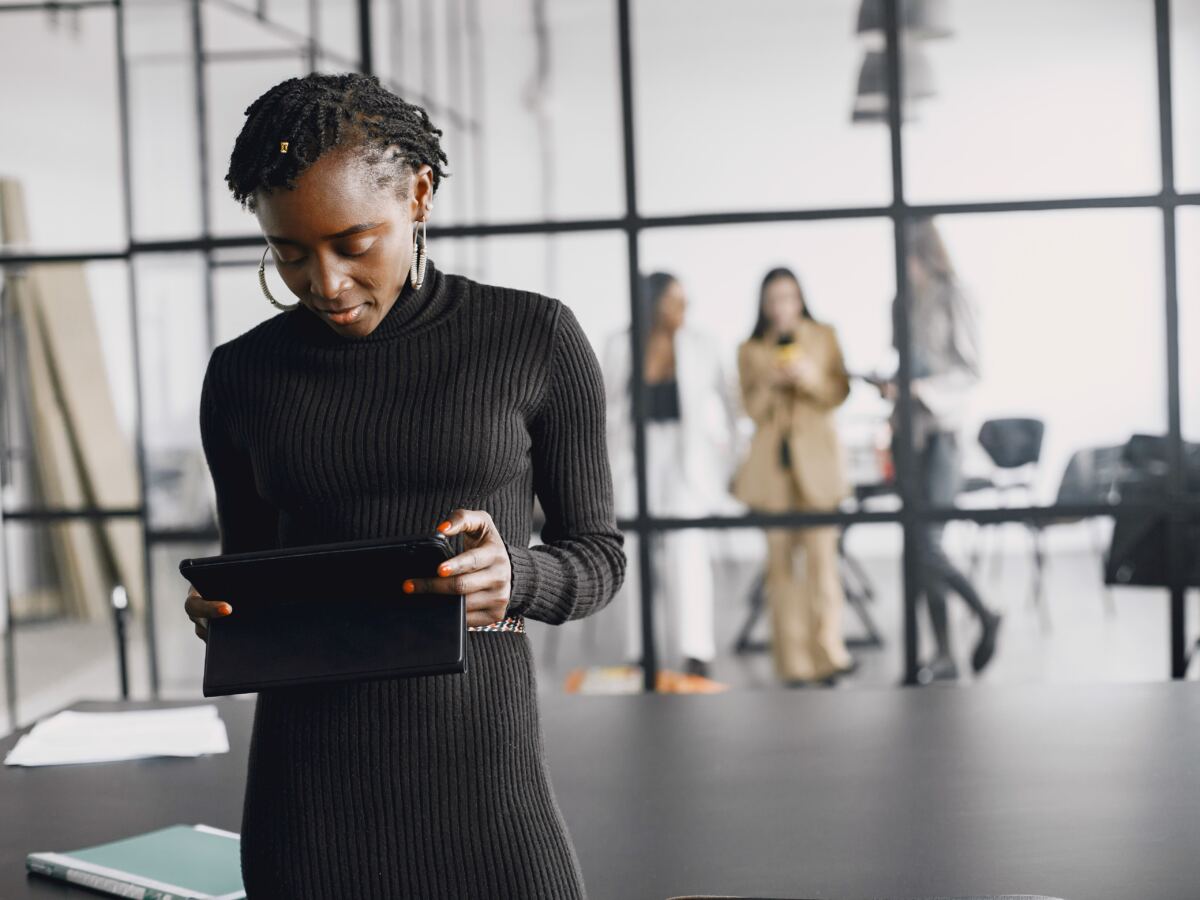 Woman in a black dress reviewing work on a tablet in a bright studio