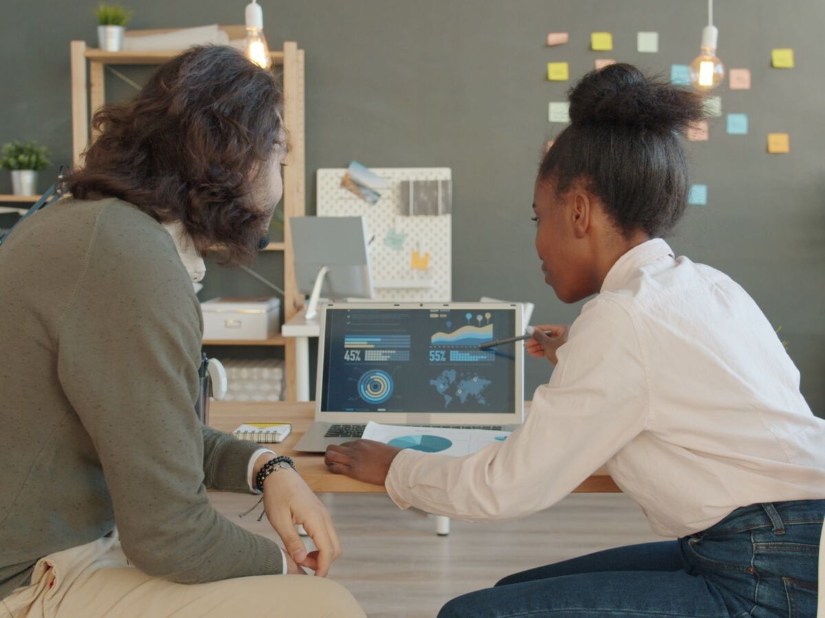 Two colleagues analysing data on a laptop in a modern office