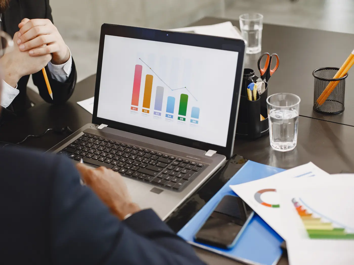 Colleagues reviewing bar charts on a laptop during a meeting