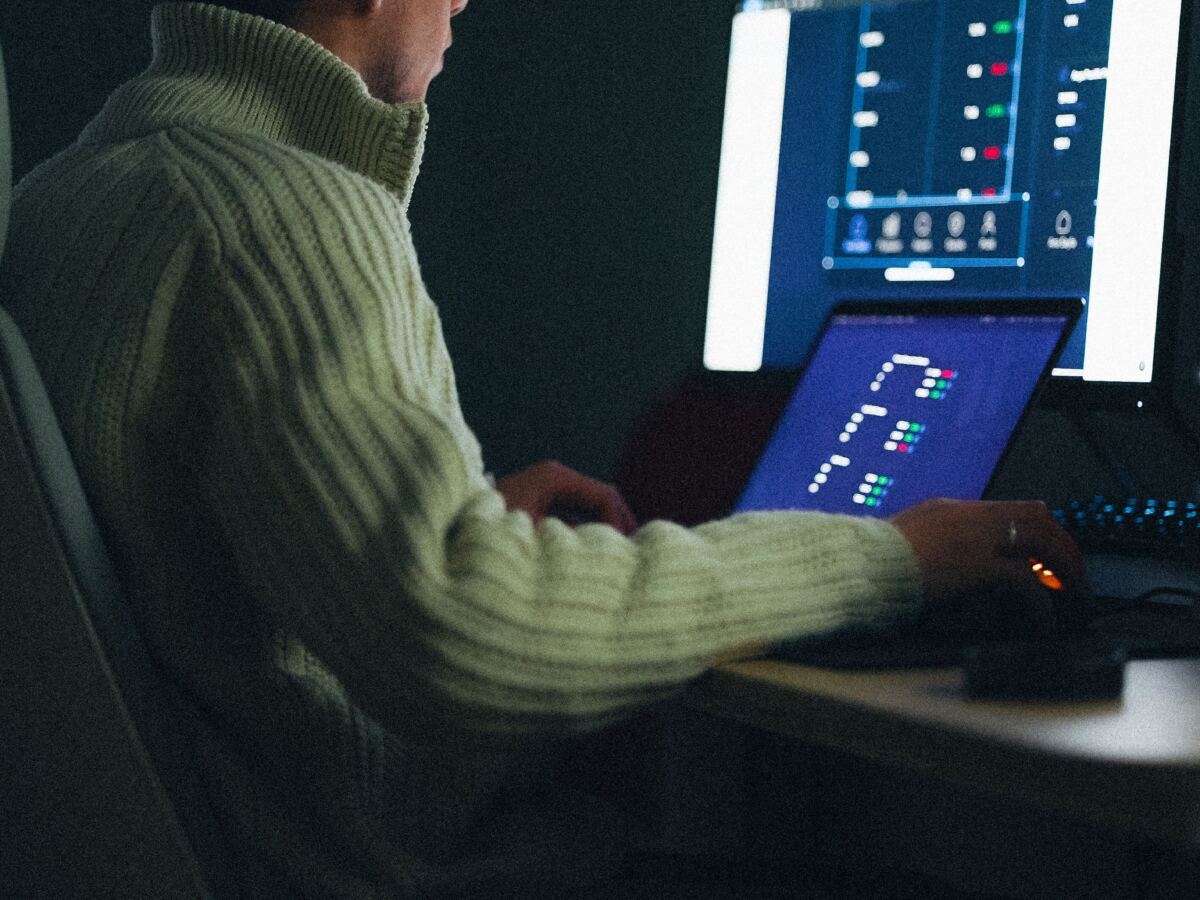 Analyst working at a desk with data dashboards on two screens