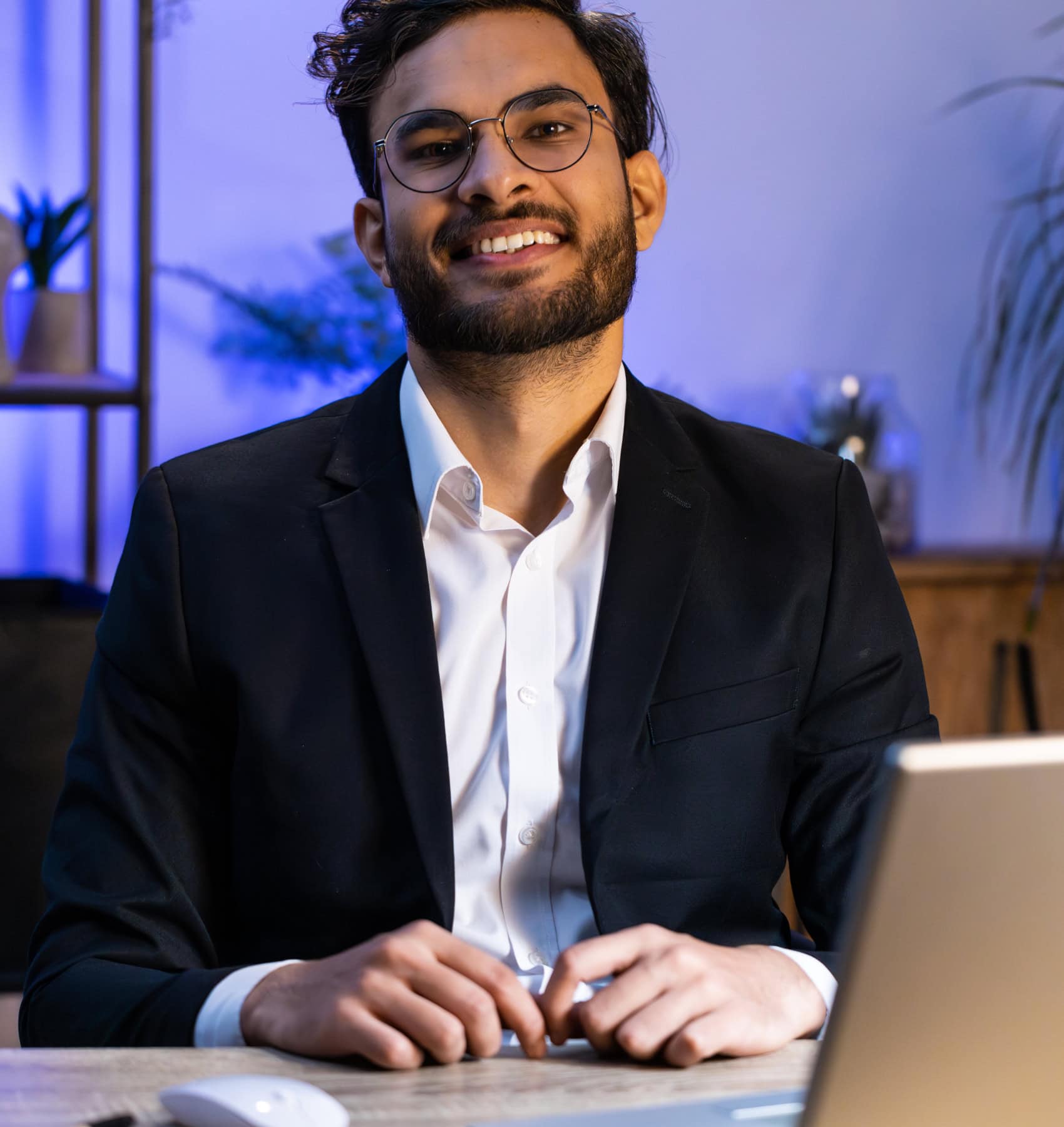 Smiling businessman in a suit working at his laptop