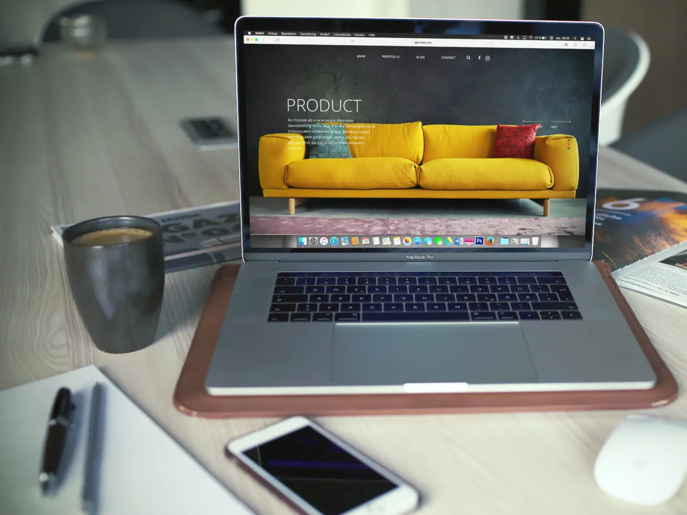 Laptop showing an online furniture store next to a mug and phone
