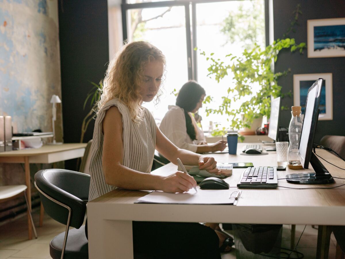 Two women working at computers in a bright office