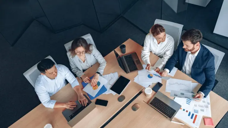 Overhead view of a team working on laptops around a meeting table