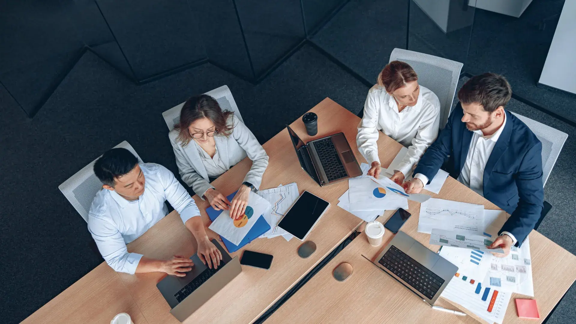 Overhead view of a team working on laptops around a meeting table