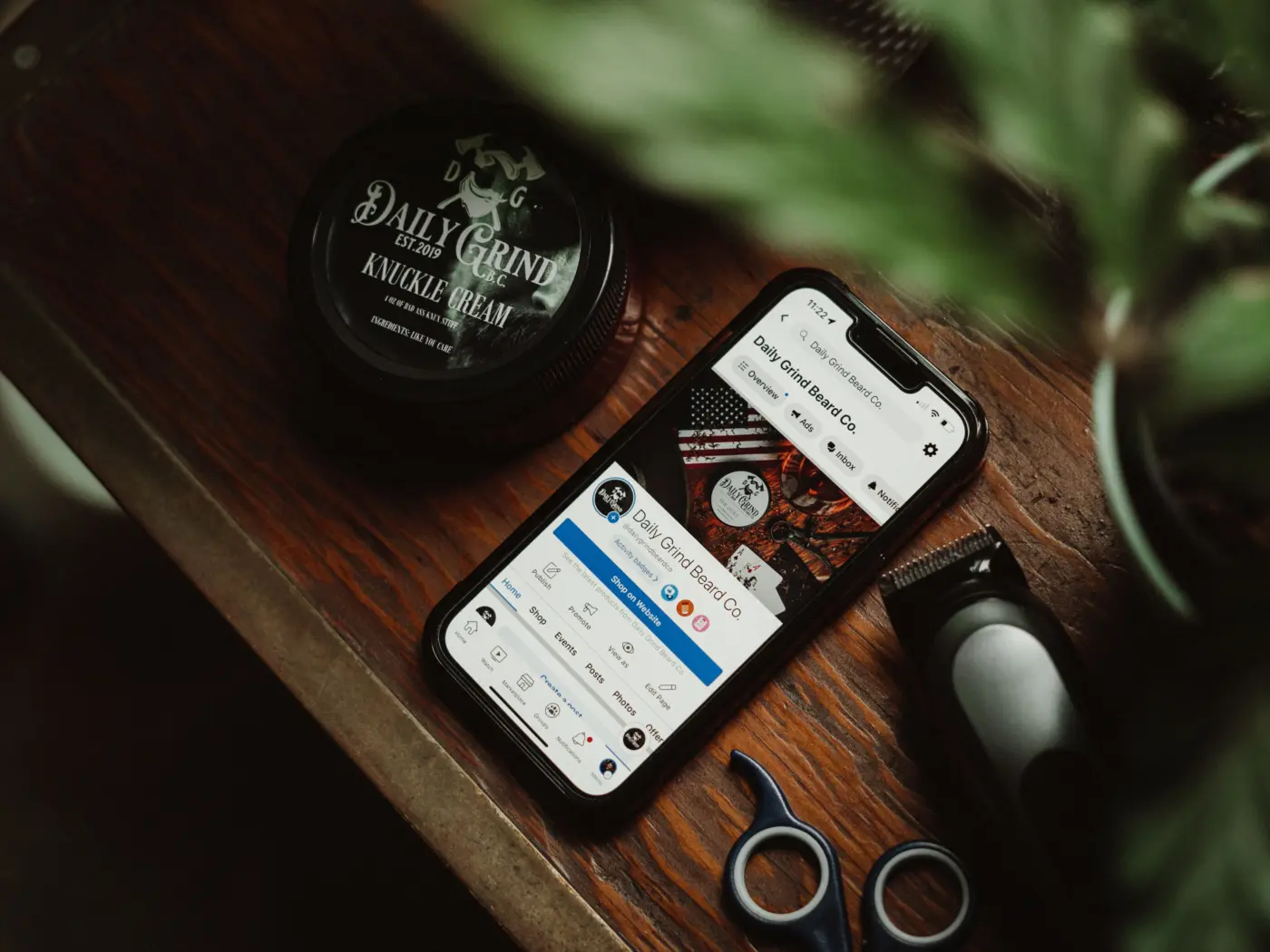 Phone showing a brand social media profile on a wooden table beside grooming products