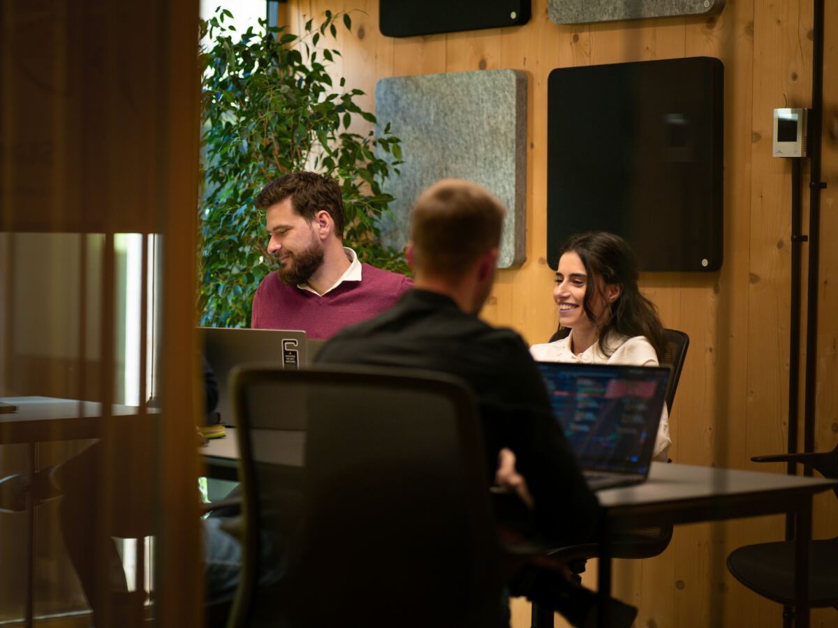 Team working together around a table with laptops in a warm, wood-panelled office