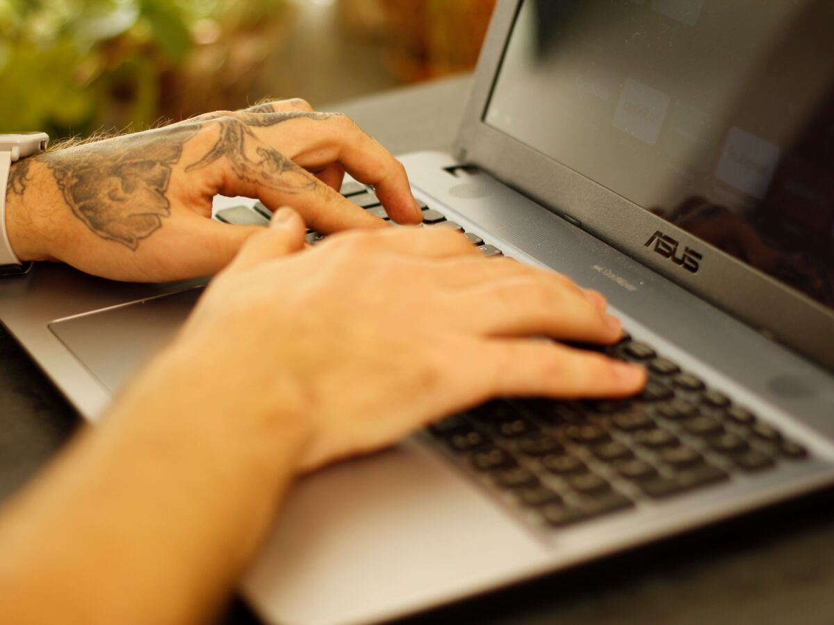 Close-up of hands typing on a laptop keyboard