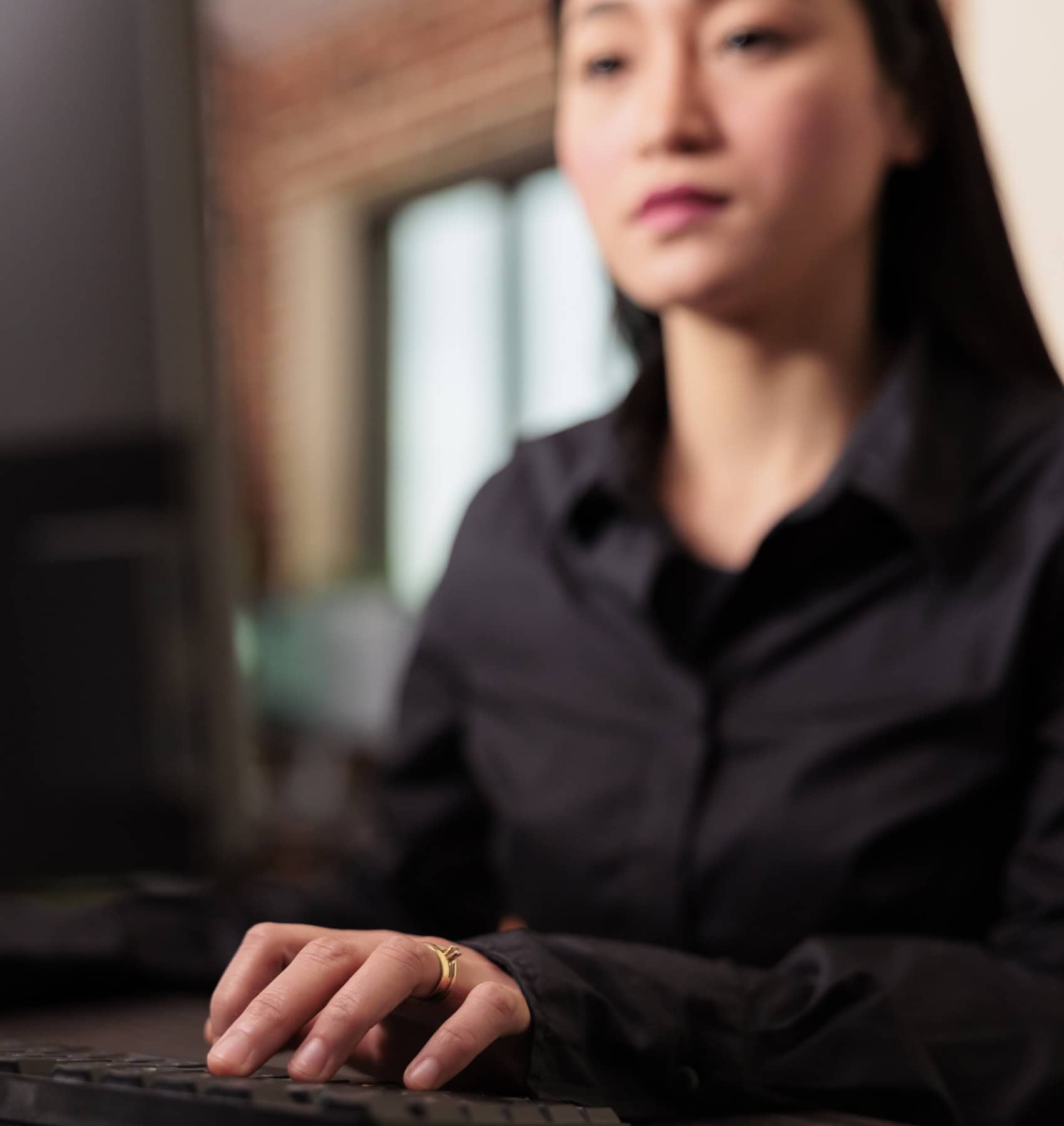 Woman concentrating while typing at a desk in a softly lit office