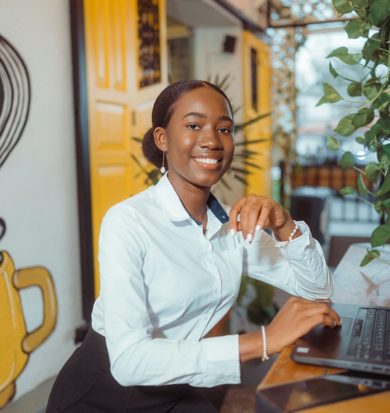 Smiling businesswoman in a white shirt at her laptop in a bright office