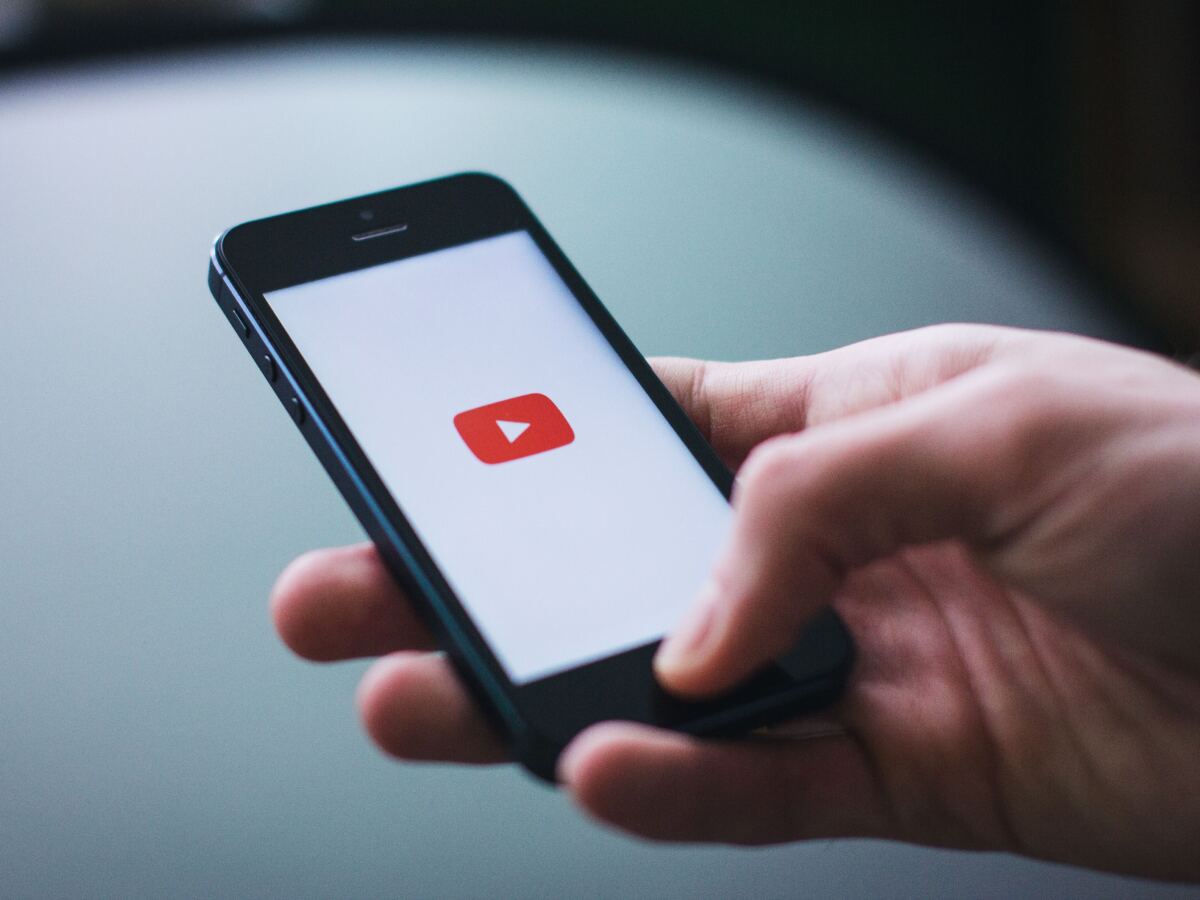 Hand holding a smartphone with the YouTube app open