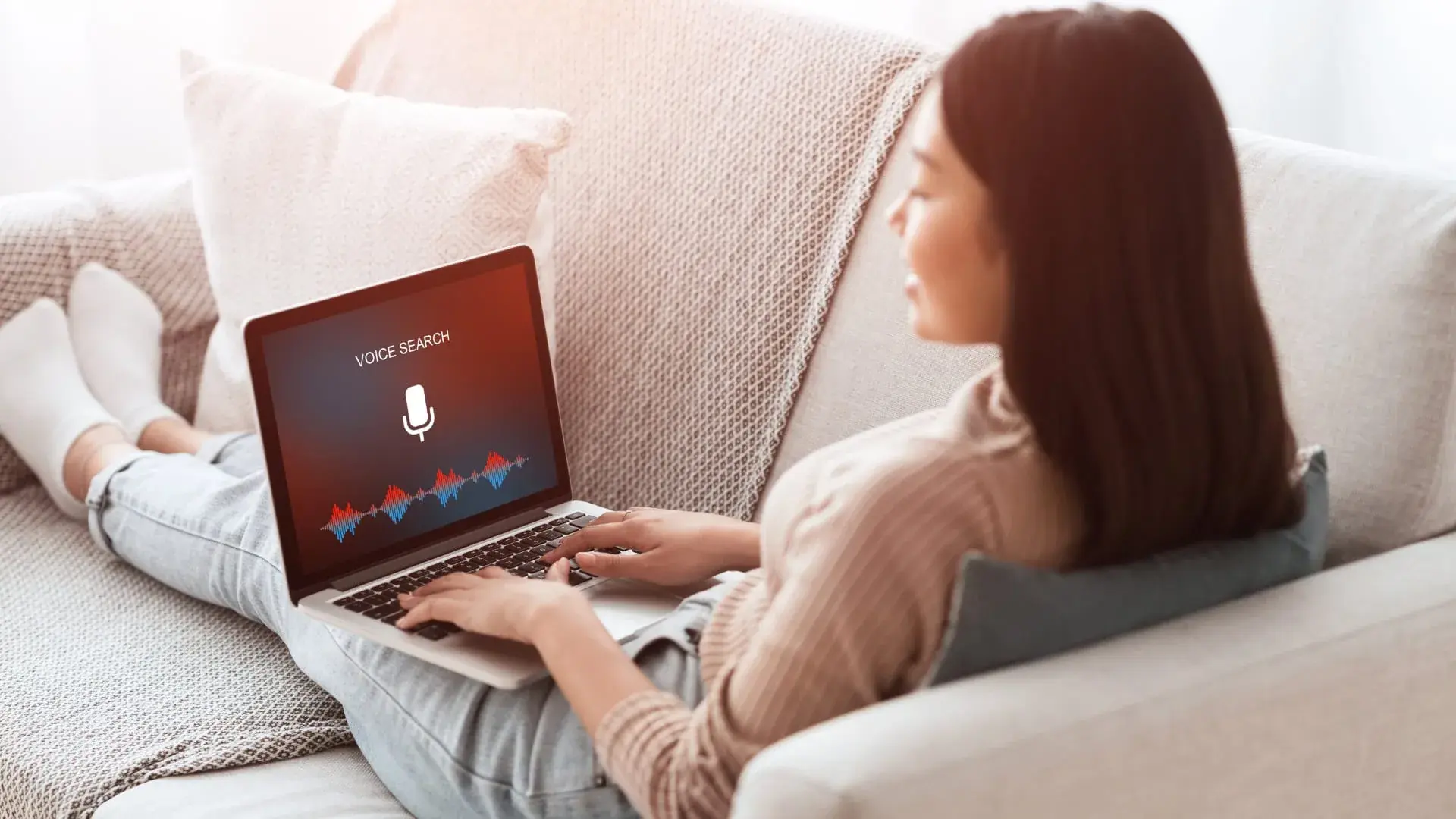 Woman on a sofa using voice search on her laptop
