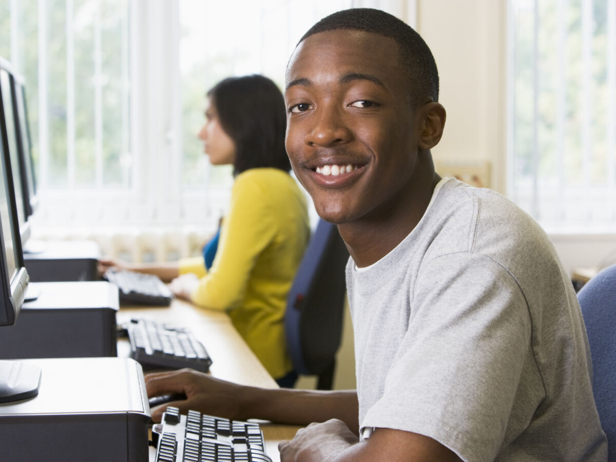 Smiling student at a computer in a busy computer lab