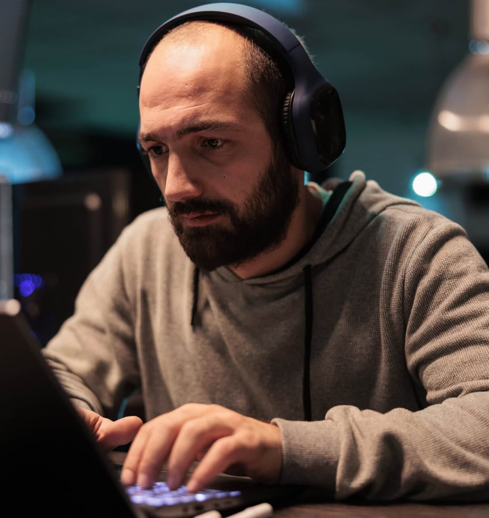 Man wearing headphones working on a laptop at night
